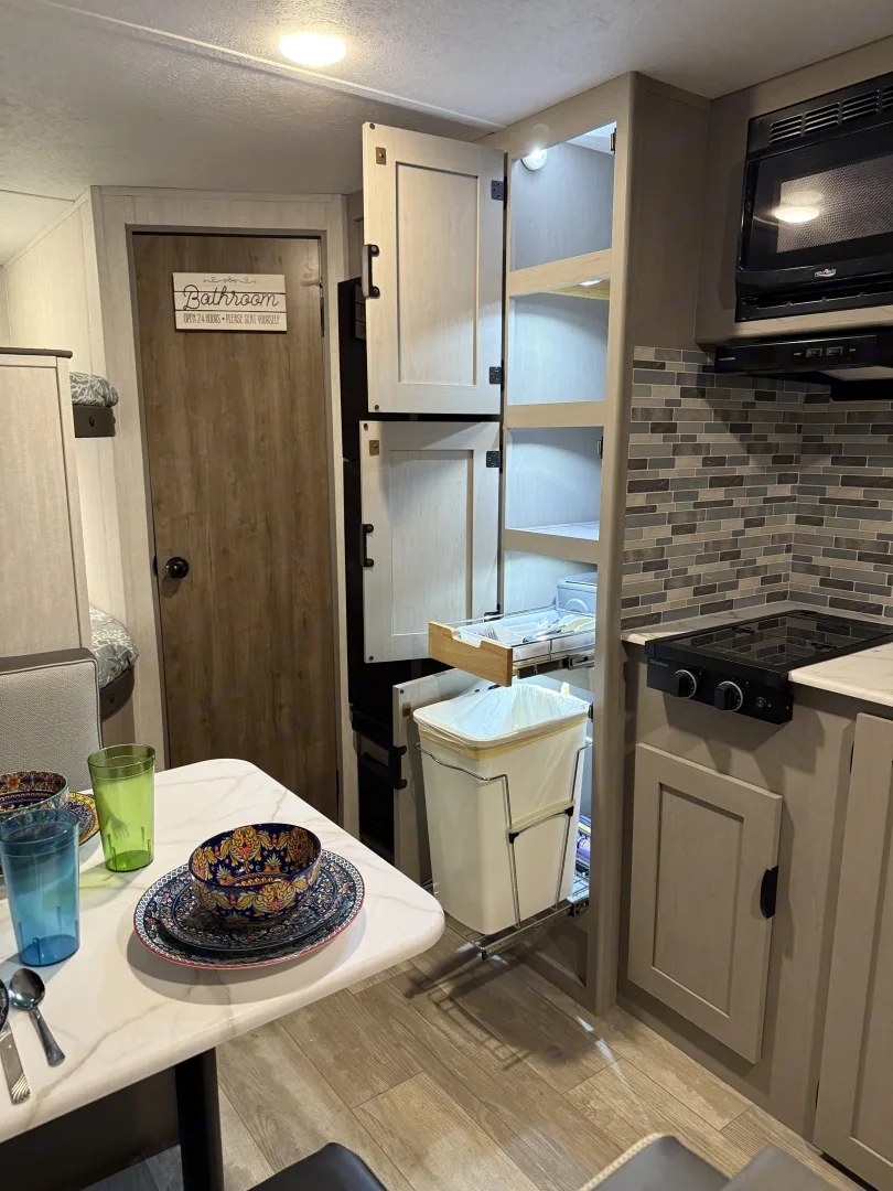 Kitchen pantry open with pull-out trash drawer